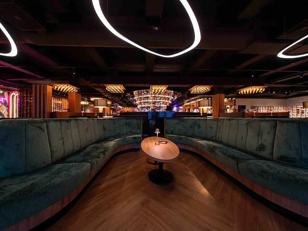 Lounge mit grünen Samtsofas und Ringleuchten